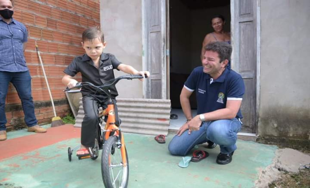 No bairro Placas, Gladson presenteia criança com bicicleta e conversa com moradores